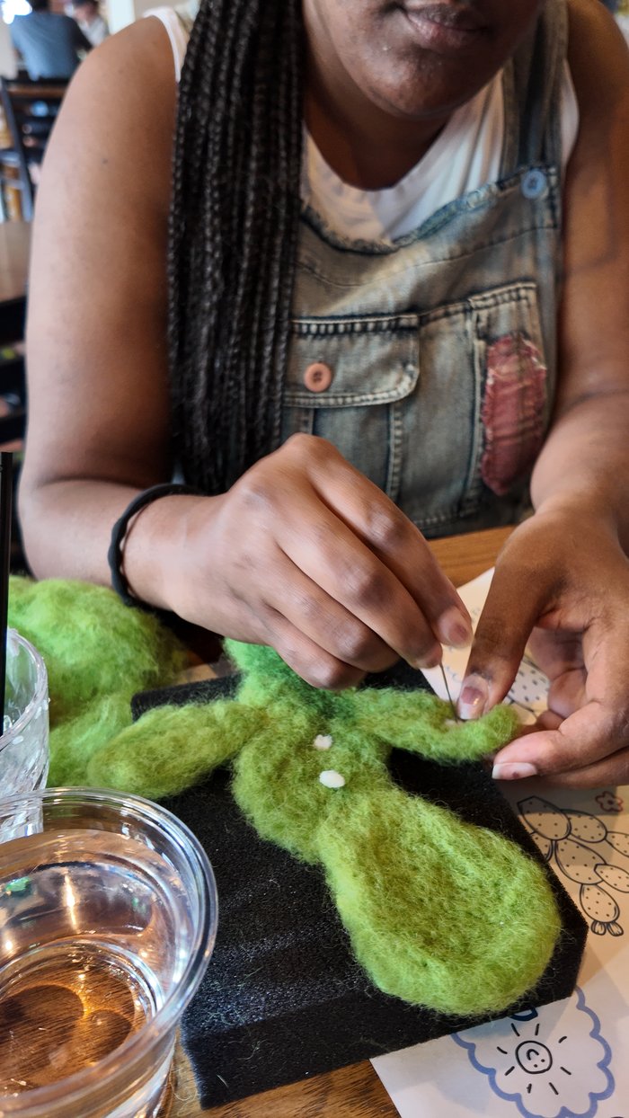 A workshop participant needle-felting a cactus shape