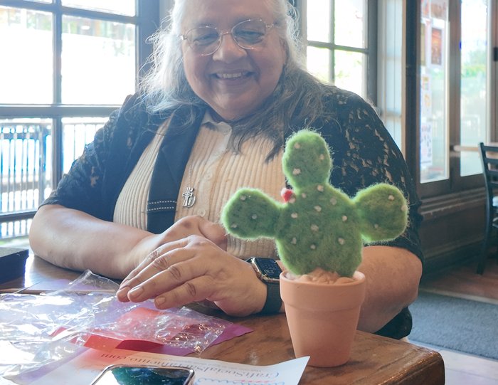 A smiling workshop participant with her finished felted cactus