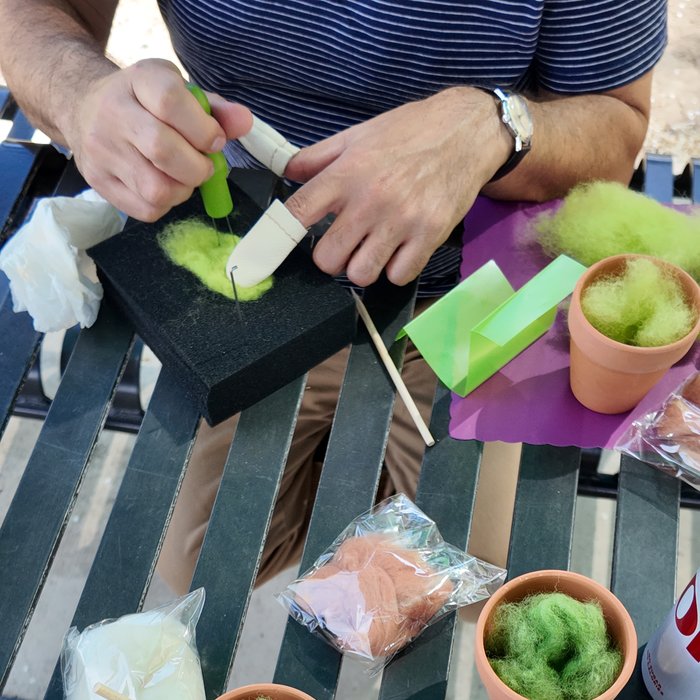 Hands needle-felting green wool roving outdoors
