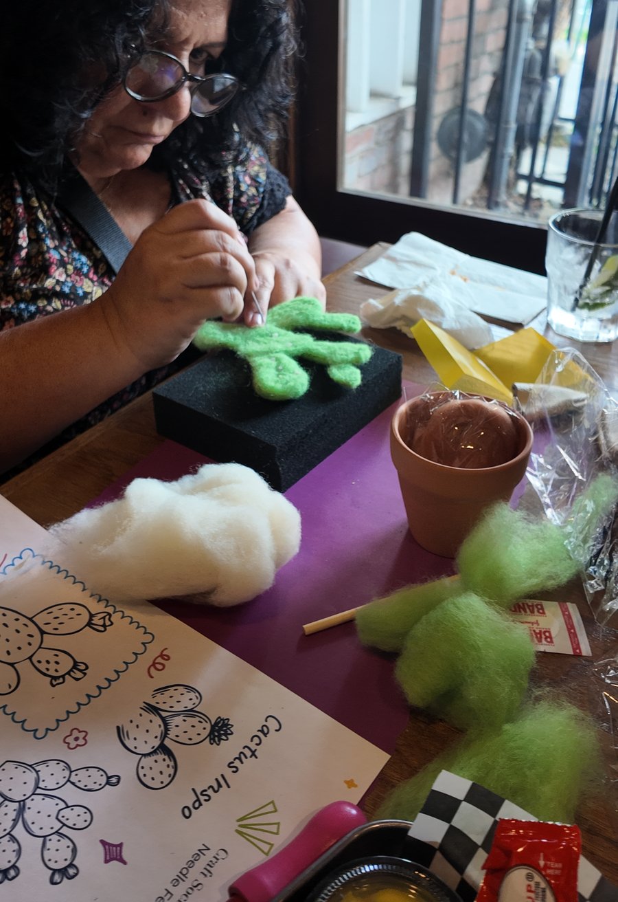 A workshop participant needle-felting a cactus