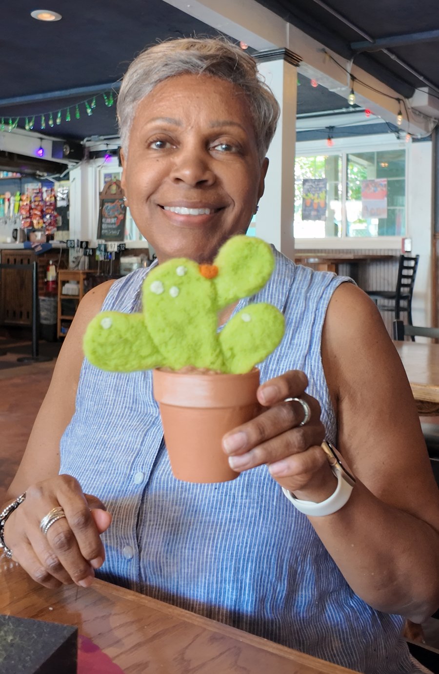 A smiling workshop participant holding her finished felted cactus